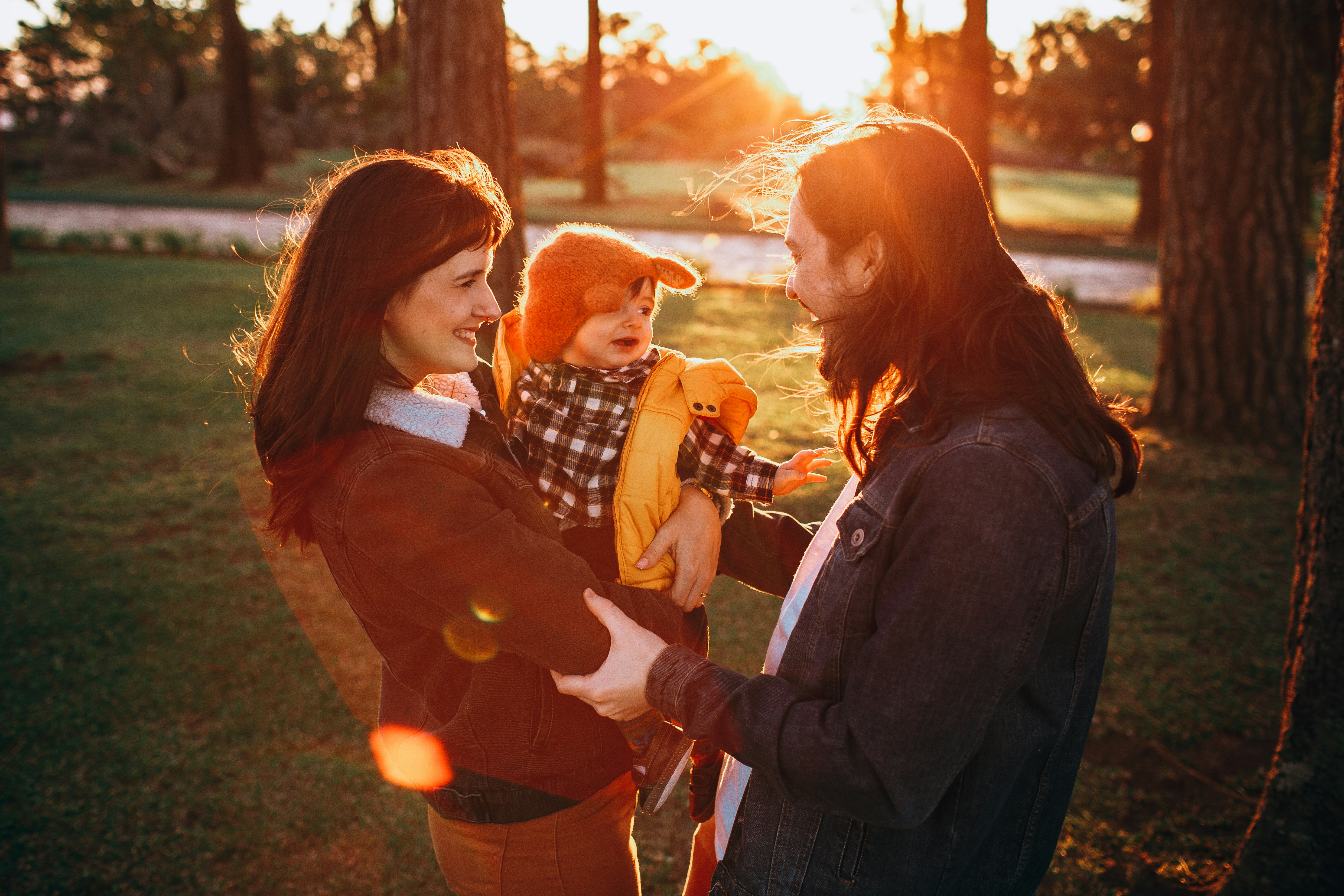 woman in black jacket carrying baby in white and black checkered dress shirt during daytime